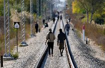 Migrants walk on the railway tracks near a border line between Serbia and Hungary, near village of Horgos, Serbia, Oct. 20, 2022. 