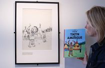 مديرة "آر كوريال" في بلجيكا  فينسيان دو ترو تقف أمام الرسم الأصلي لغلاف مجلّد قصة "تان تان في الولايات المتحدة" الذي أصدر عام 1942.