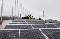 Workers mount solar panels on the roof of the Olympic Stadium or Olympiastadion in Berlin, Germany