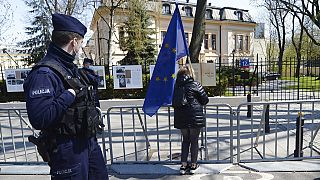 A woman holds a European Union flag outside the Constitutional Tribunal, background, in Warsaw, Poland, on April 28, 2021.
