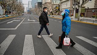 A woman wearing a face shield and mask amid the Covid-19 pandemic walks on a street in the Jing'an district in Shanghai