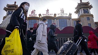 Des passants portant le masque devant une station de métro de Pékin, en Chine. 