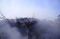 Locals watch the wreckage of a passenger plane in Pokhara, Nepal, Sunday, Jan.15, 2023.