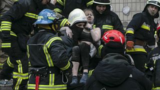 Emergency workers carry a wounded woman after a Russian rocket hit a multistory building on Saturday in Dnipro, Ukraine, Sunday, Jan. 15, 2023