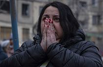 Schockiert schaut eine Frau in Dnipro auf die Trümmer eines Wohnhauses, in dem 1.700 Menschen lebten, und das von einer russischen Rakete getroffen wurde.
