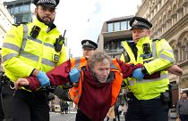 عکس از افسران پلیس که یکی از فعالان گروه Just Stop Oil را پس از بستن جاده ای در لندن در روز پنجشنبه ۲۷ اکتبر ۲۰۲۲ دستگیر کردند