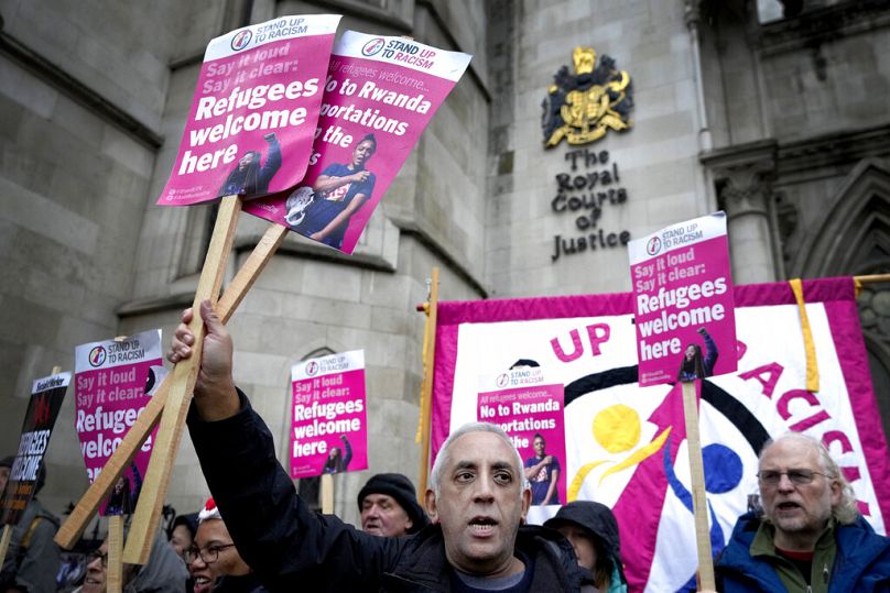 Des militants de la campagne "Stand Up To Racism" tiennent des banderoles devant la Haute Cour à Londres, décembre 2022.