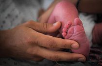 Édesanya tartja újszülöttje lábát a franciaországi Lille kórházában, 2018 júliusában