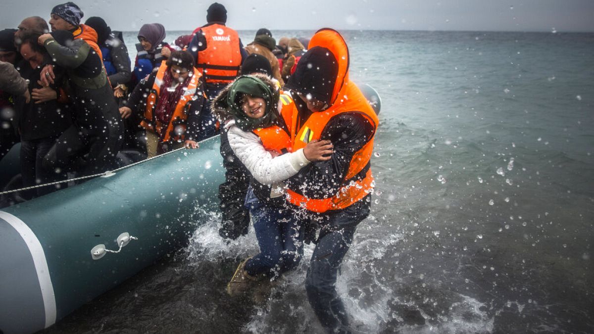 Jan. 3, 2016 file photo, refugees and migrants disembark on a beach after crossing a part of the Aegean sea from Turkey.