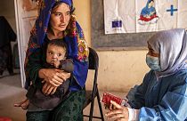 Save the Children nutrition counsellor, right, explains to Nelab how to feed her 11-month-old daughter with therapeutic food, in Sar-e-Pul, Afghanistan, Sept. 29, 2022 2