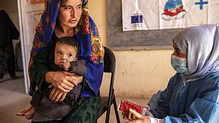 Save the Children nutrition counsellor, right, explains to Nelab how to feed her 11-month-old daughter with therapeutic food, in Sar-e-Pul, Afghanistan, Sept. 29, 2022 2
