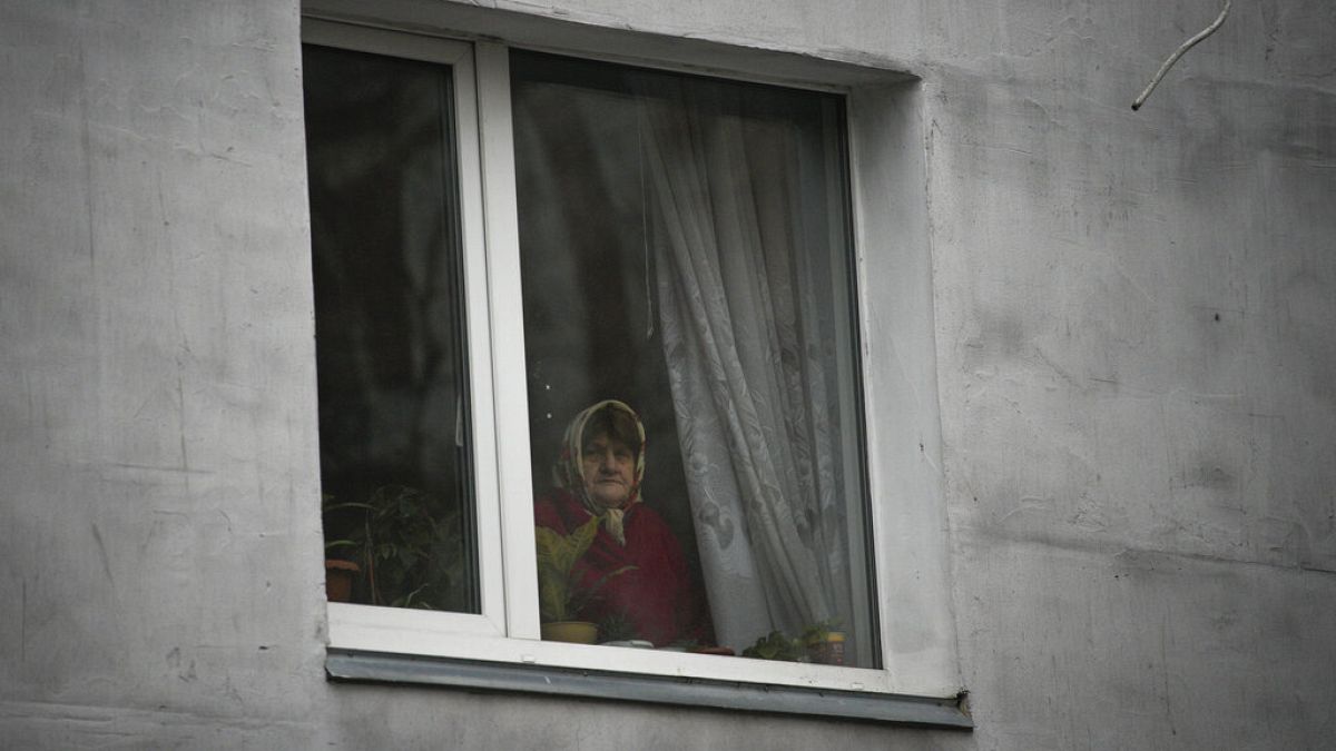 Kijev külvárosában egy asszony az ablakából nézi a tragédia nyomait