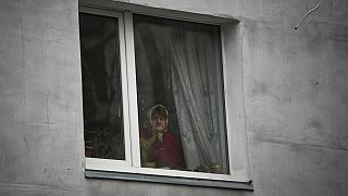 Kijev külvárosában egy asszony az ablakából nézi a tragédia nyomait