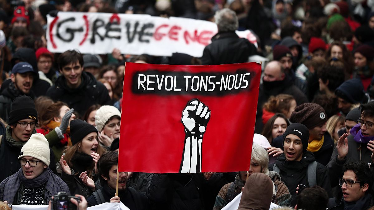 Protesters holding a banner with a fist and the text meaning 'Rise against' in Paris, France in 2019