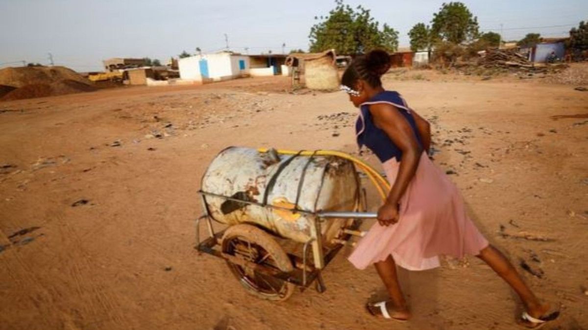 A woman pushes a barrel filled with water on the outskirts of Ouagadougou, Burkina Faso 