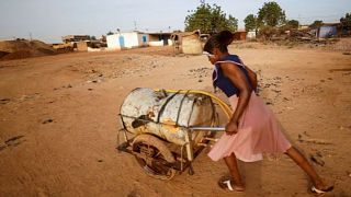 A woman pushes a barrel filled with water on the outskirts of Ouagadougou, Burkina Faso 