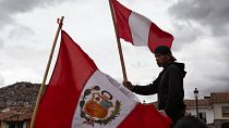 A person waves a Peruvian flag while waiting for other union groups to arrive at Plaza de Armas to join anti-government protests in Cusco, Peru