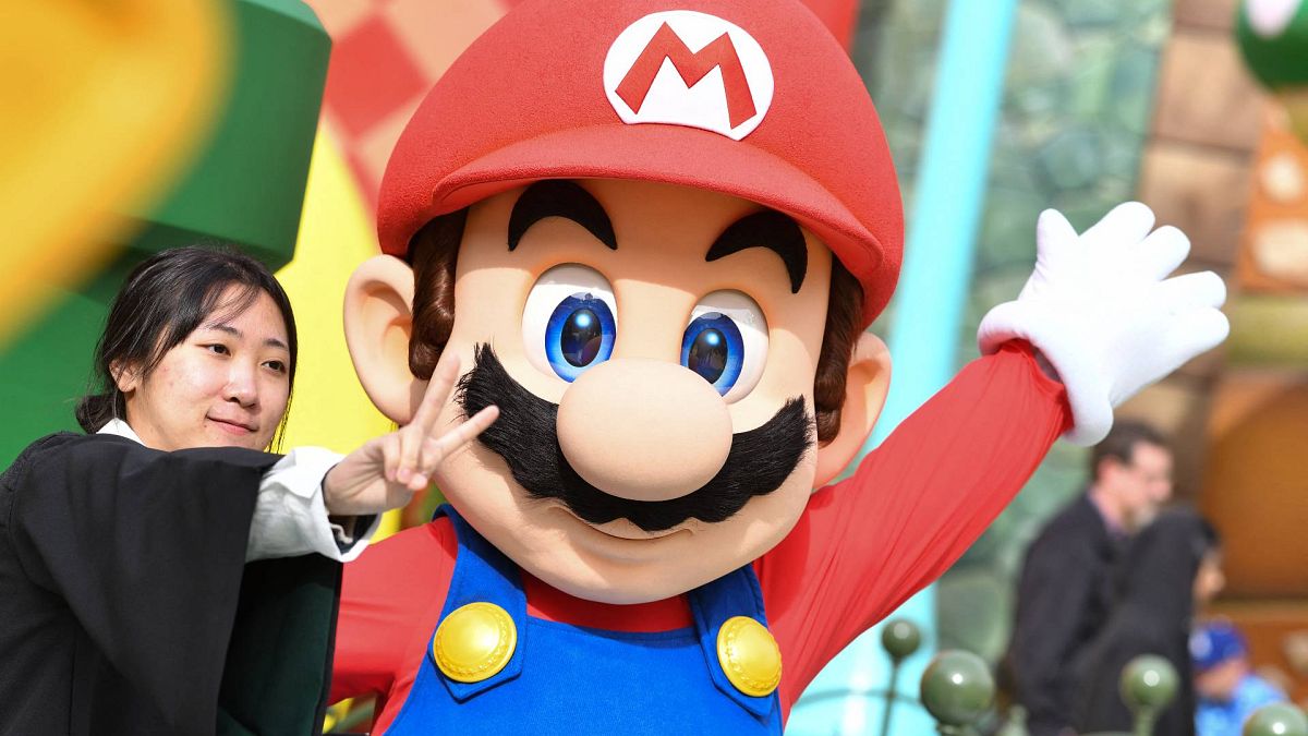 A guest takes a photo with Mario during a preview of Super Nintendo World at Universal Studios in Los Angeles, California,