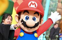 A guest takes a photo with Mario during a preview of Super Nintendo World at Universal Studios in Los Angeles, California,
