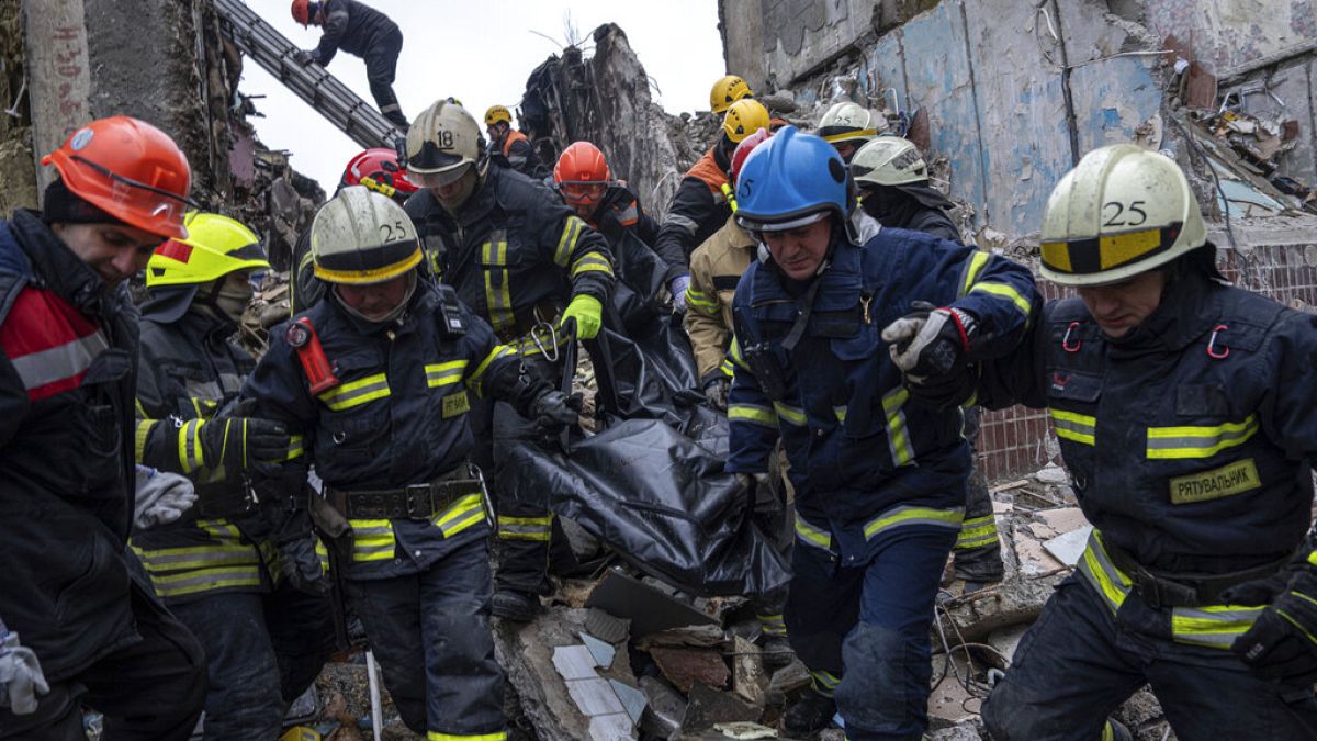 رجال الإنقاذ ينتشلون جثة من بين أنقاض المبنى الذي قصفته روسيا