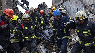 Rescue workers carry the body of a man who was killed in a Russian missile strike on an apartment building in the southeastern city of Dnipro, Ukraine, Monday 16 Jan 2023