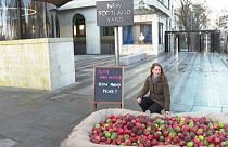Refuge CEO Ruth Davison crouches next to the pile of rotten apples outside the Metropolitan Police headquarters in London.