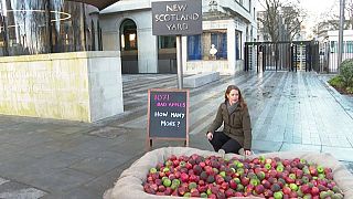 Refuge CEO Ruth Davison crouches next to the pile of rotten apples outside the Metropolitan Police headquarters in London.