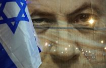 بنری از چهره بنیامین نتانیاهو نخست وزیر اسرائیل و پرچم این کشور در حاشیه تظاهرات شنبه ۲۱ ژانویه در تل‌آویو