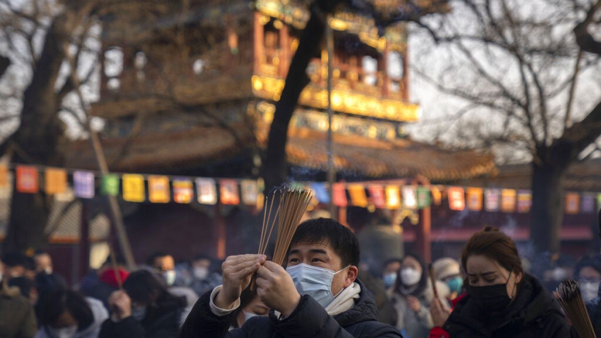 Visitors burn incense as they pray on the first day of the Lunar New Year holiday at the Lama Temple in Beijing, Sunday, Jan. 22, 2023. 
