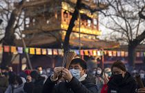 Visitors burn incense as they pray on the first day of the Lunar New Year holiday at the Lama Temple in Beijing, Sunday, Jan. 22, 2023.