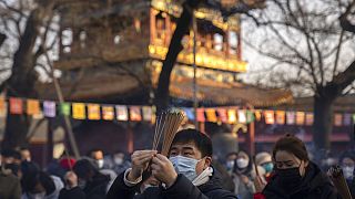 Visitors burn incense as they pray on the first day of the Lunar New Year holiday at the Lama Temple in Beijing, Sunday, Jan. 22, 2023. 