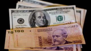 اسکناس یکصد پزویی آرژانتین در کنار اسکناس دلار آمریکا 