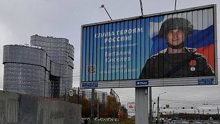 A poster displaying a Russian soldier with a slogan reading 'Glory to the Heroes of Russia' near the 'PMC Wagner Centre' in Saint Petersburg