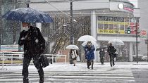 مواطنون يعبرون الشارع أثناء تساقط الثلوج في مدينة توياما بمحافظة توياما غربي اليابان، حيث تستعد أجزاء من البلاد لعاصفة شتوية شديدة، 24 يناير 2023.