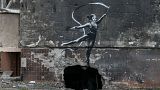 Wearing a neck brace, a rhythmic gymnast performs in a new Banksy piece painted on the wall of a residental building in Irpin, Ukraine