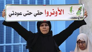 سيدة فلسطينية تحمل لافتة خلال مظاهرة خارج مقر وكالة الأمم المتحدة لإغاثة وتشغيل اللاجئين (الأونروا) في مدينة غزة ديسمبر 2022.