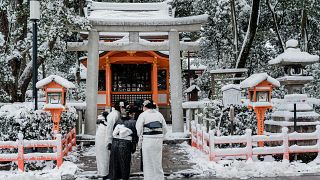 أشخاص يرتدون ملابس تقليدية أمام ضريح ياساكا في كيوتو بعد أن أثرت الثلوج الكثيفة والرياح العاتية خلال الليل على مناطق واسعة من البلاد، في 25 يناير 2023