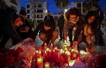 Una mujer se arrodilla junto al monumento en memoria del sacristán de una iglesia asesinado el miércoles en Algeciras, sur de España, jueves 26 de enero de 2023.