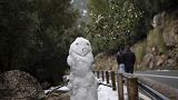 People walk past a snowman at the Serra de Tramuntana natural landscape covered with snow after the last snowfall in Palma de Mallorca, Spain, Thursday, Jan. 26, 2023.
