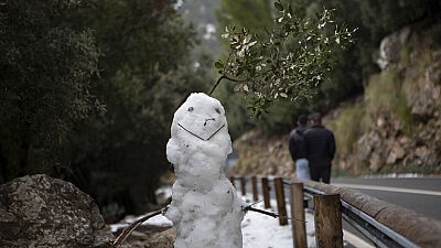 People walk past a snowman at the Serra de Tramuntana natural landscape covered with snow after the last snowfall in Palma de Mallorca, Spain, Thursday, Jan. 26, 2023.