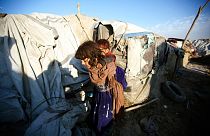 Afganistan'ın başkenti Kabil'e yakın mesafedeki Teymeni mülteci kampında, kardeşini sırtına alan bir kız çocuğu