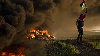 Palestinians burn tyres and wave the national flag during a protest against Israeli military raid in the West Bank city of Jenin, along the border fence with Israel