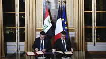 الرئيس الفرنسي إيمانويل ماكرون (يمين) ورئيس الوزراء العراقي محمد شياع السوداني يوقعان اتفاقية في باريس 
