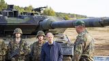 Deutschlands Kanzler Olaf Scholz mit Bundeswehrsoldaten vor einem Leopard-Panzer.