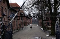 مردی در کنار دروازه "Arbeit Macht Frei" (کار شما را آزاد می کند) در اردوگاه کار اجباری و کشتار آلمان نازی سابق آشویتس-بیرکناو در لهستان، پنجشنبه، ۲۶ ژانویه ۲۰۲۳