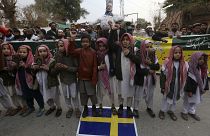 أطفال يحملون "القرآن" ويقفون فوق علم السويد خلال مظاهرة في بيشاور، باكستان.