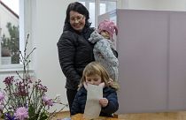 A child casts her mother's ballot at the presidential elections runoff in Pruhonice, Czech Republic.