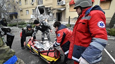 Ukrainian medics carry the body of a local resident killed in a residential building after a Russian shelling in Kherson, southern Ukraine, on January 29, 2023