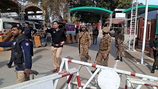 Army soldiers and police officers clear the way for ambulances rushing toward a bomb explosion site, at the main entry gate of police offices, in Peshawar, Pakistan, Monday, J