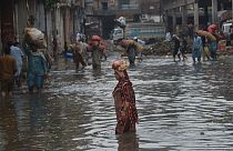 Pakistani commuters people wade through a flooded road at Badami Bagh vegetable market after heavy monsoon rain spell in provincial capital city Lahore. 